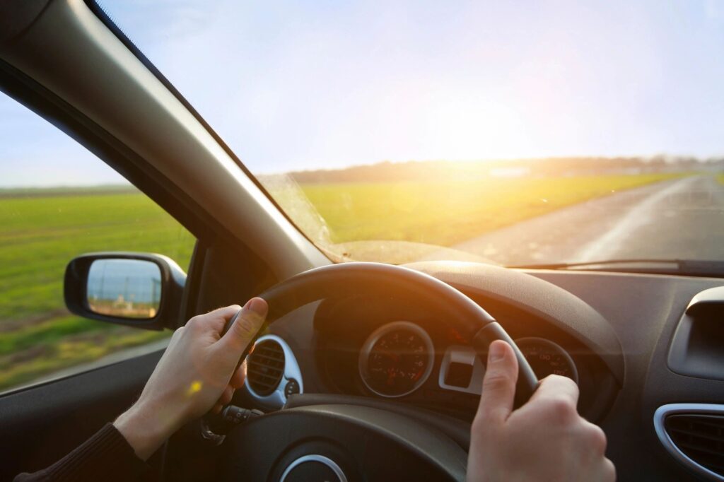 A person confidently driving a car on a sunny day, highlighting safe and smooth vehicle performance after regular maintenance.