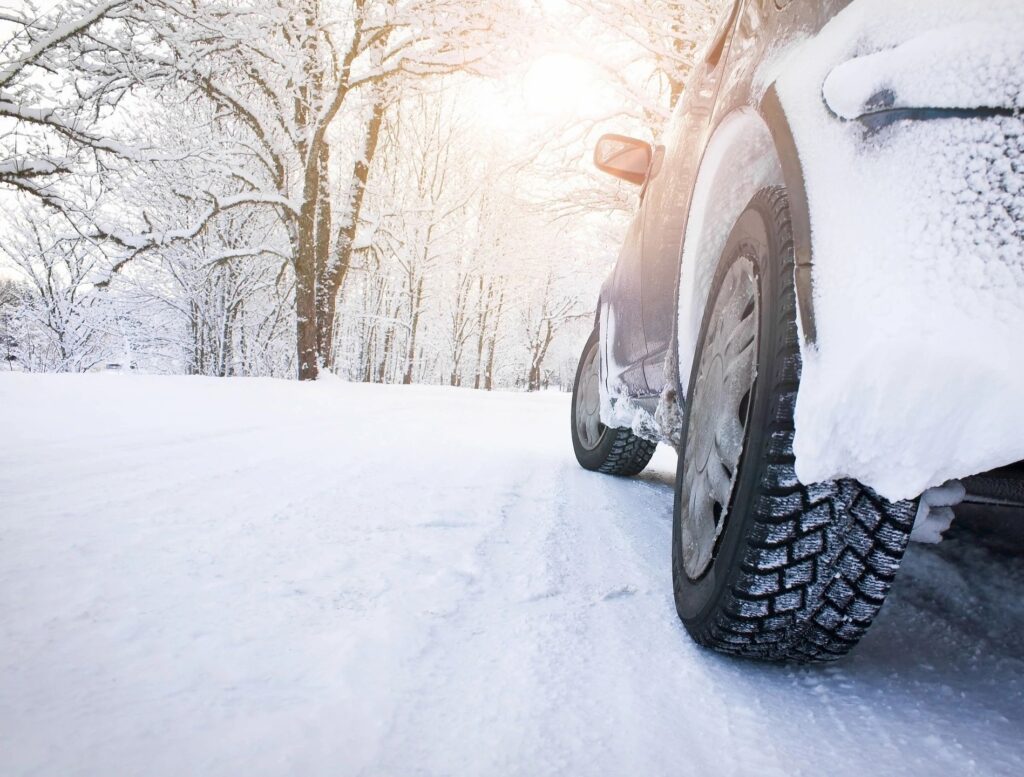 car in snow parked on a winter road, emphasizing the importance of seasonal car care and preparation for safe driving in snowy conditions