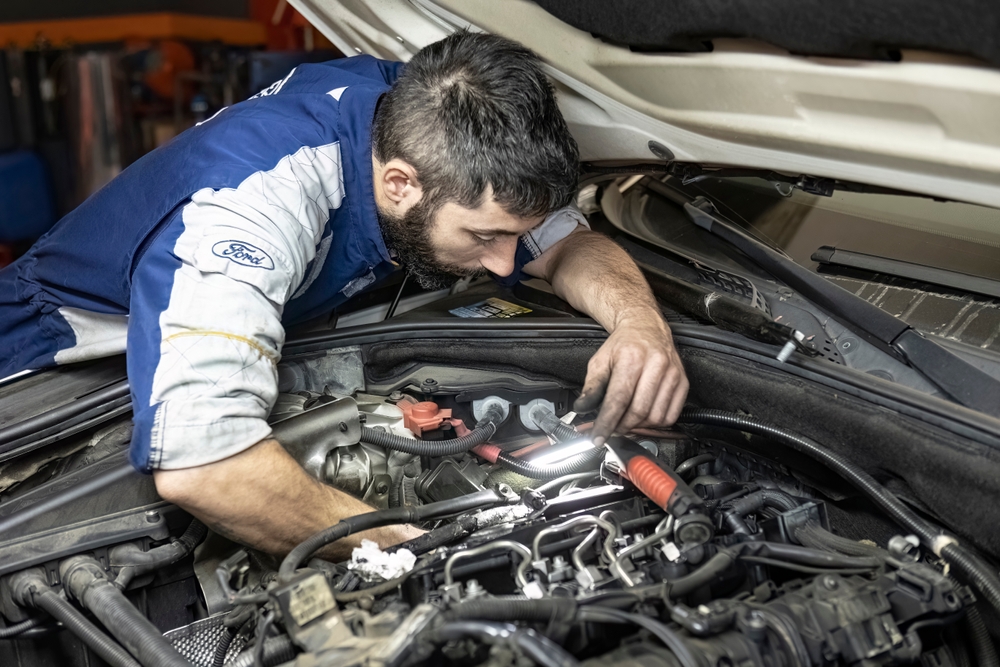 Ford-certified mechanic performing engine diagnostics on a Ford vehicle at an auto repair shop in Salem, Oregon.